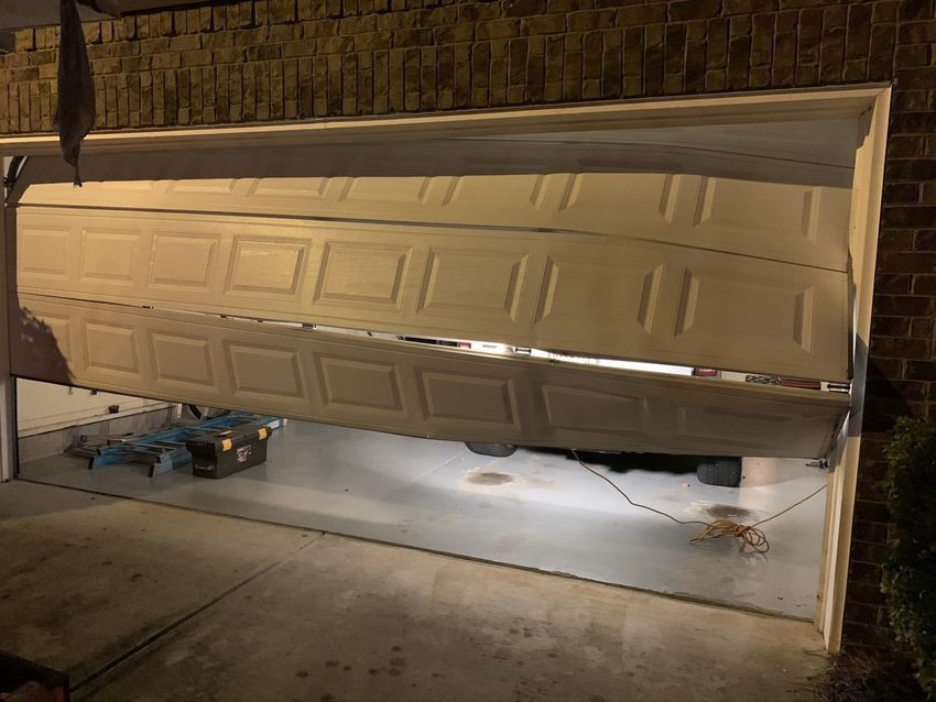 Partially open garage door with a car visible underneath at night