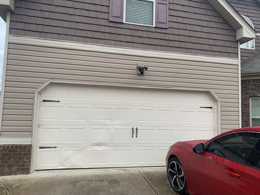 House exterior with a white garage door and a red sports car parked at the right edge.