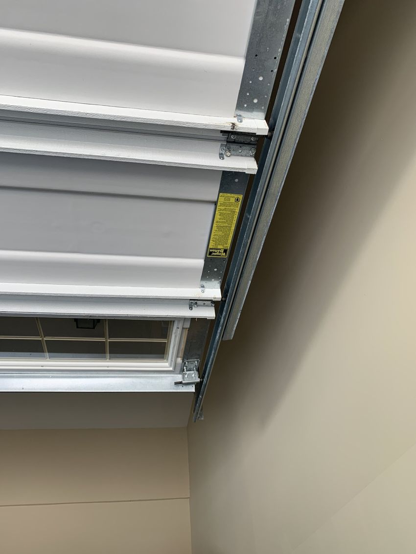 Close-up of a partially open white garage door with exposed insulation and ceiling track.