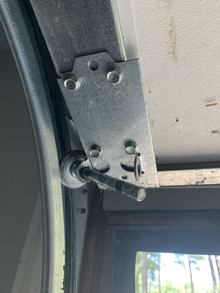 Close-up of a metal hinge and latch on a gray door frame by a window.