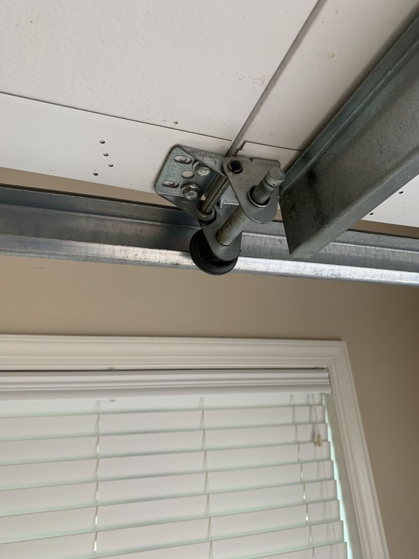 Garage door opener bracket mounted to the ceiling above a window with blinds