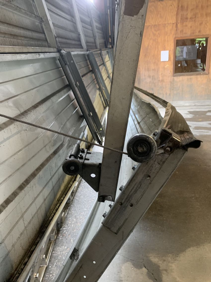 Overturned industrial machine leaning against a wall in a warehouse corridor.