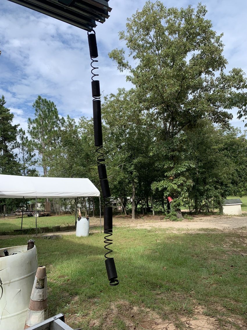 Black hanging strap under a roof in a grassy yard with trees and a white canopy tent
