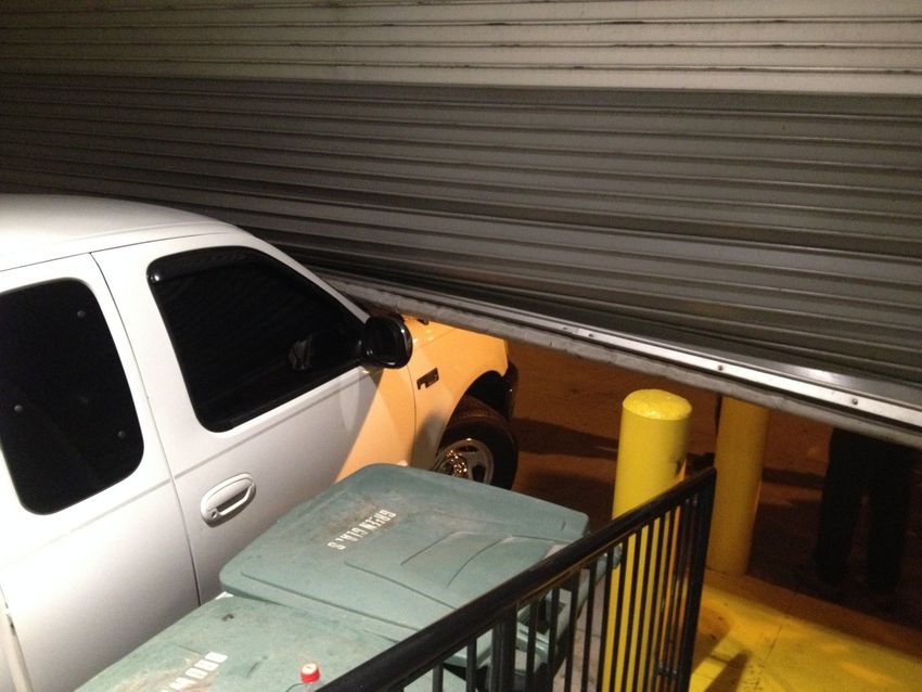 Car and trash bins squeezed against a closed garage door in a tight parking space