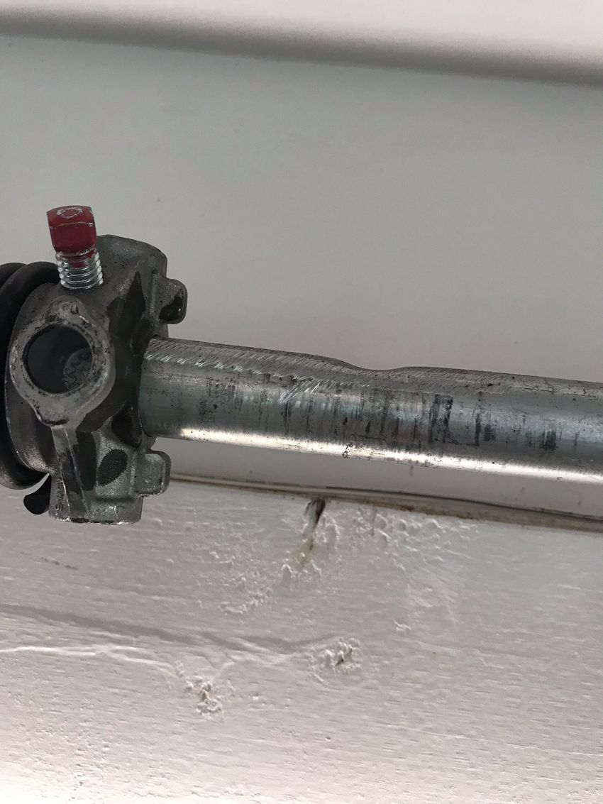 Metal pipe joint with a red cap against a white wall