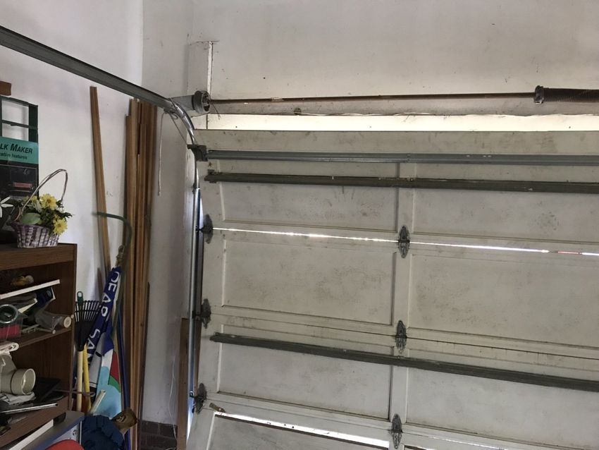 Interior of a garage with a white sectional garage door and shelving on the left