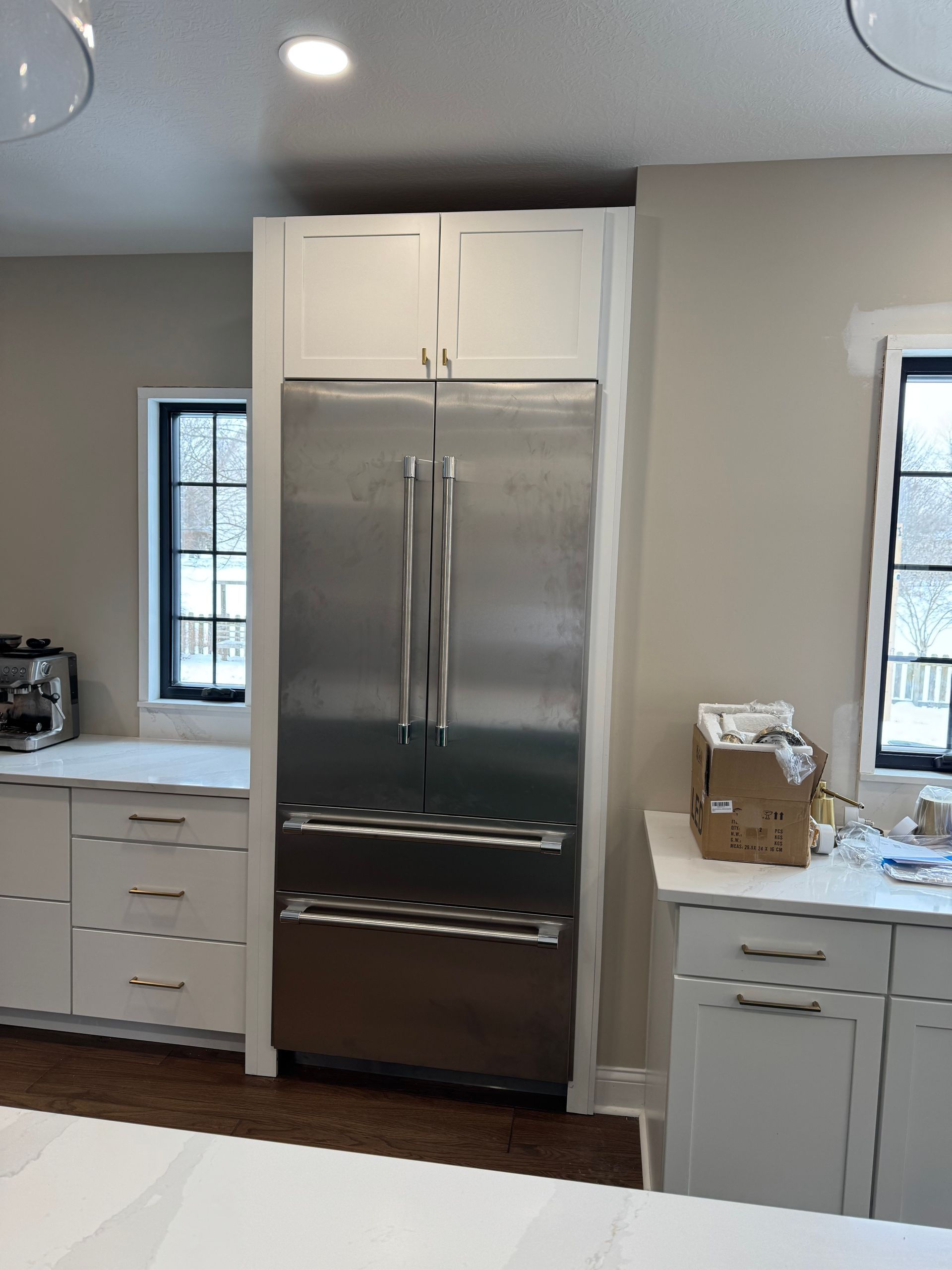 A kitchen with white cabinets and a stainless steel refrigerator