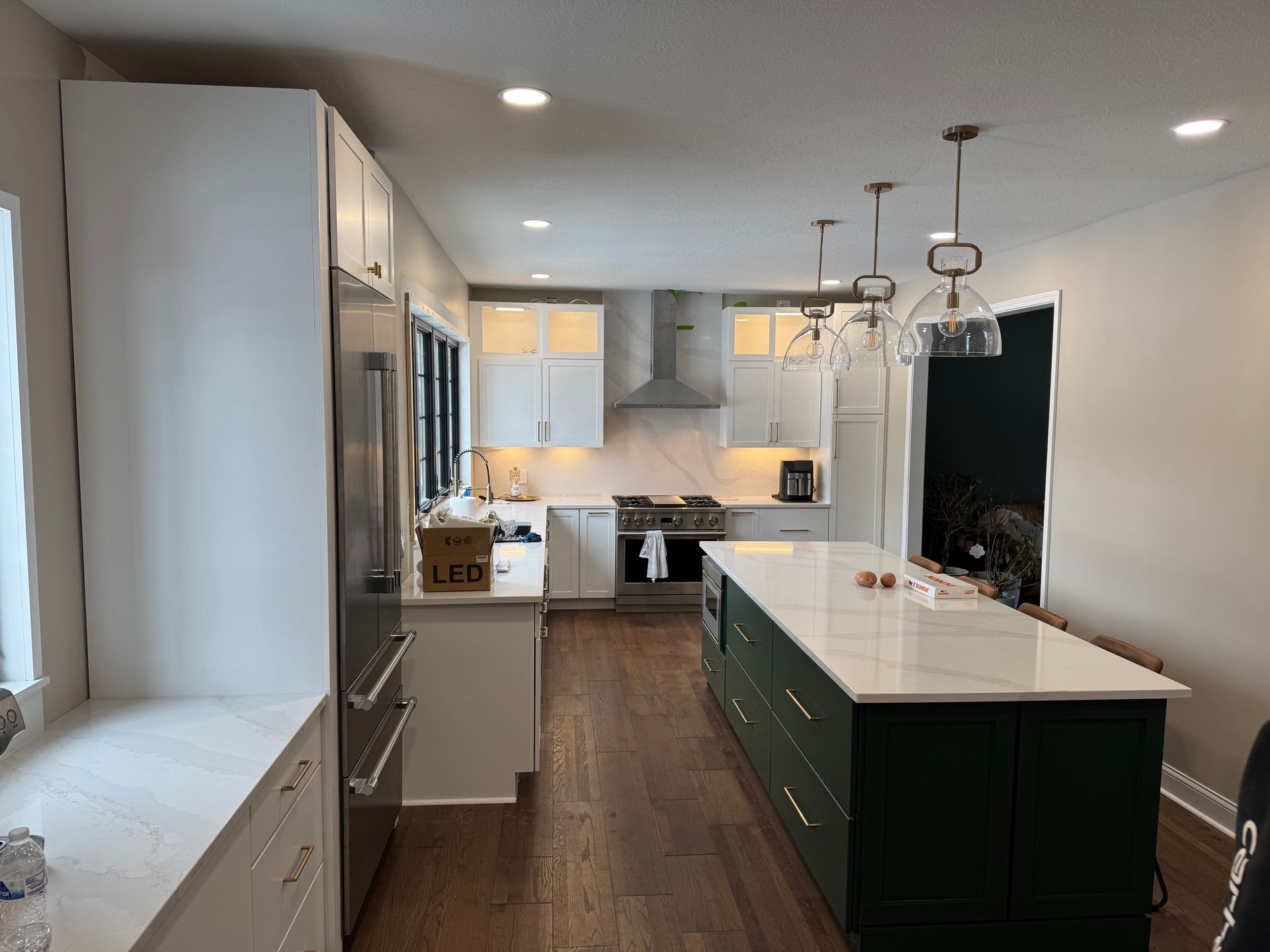 A kitchen with white cabinets , stainless steel appliances , and a large green island.