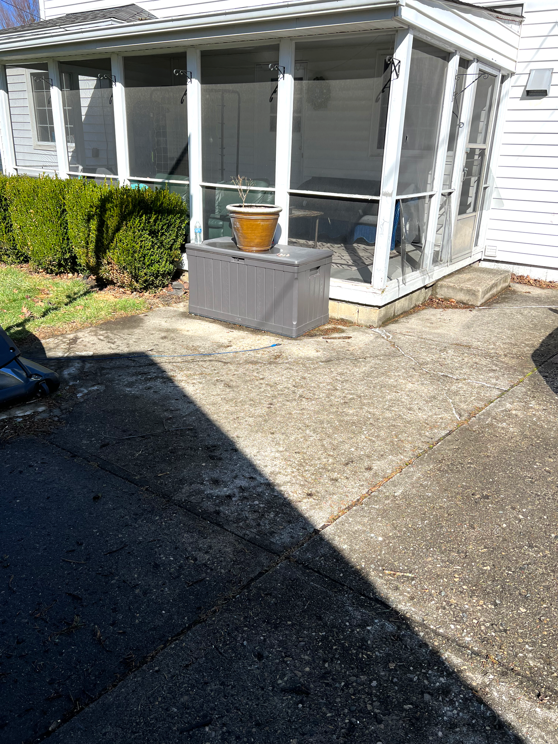 A screened in porch with a potted plant in front of it.
