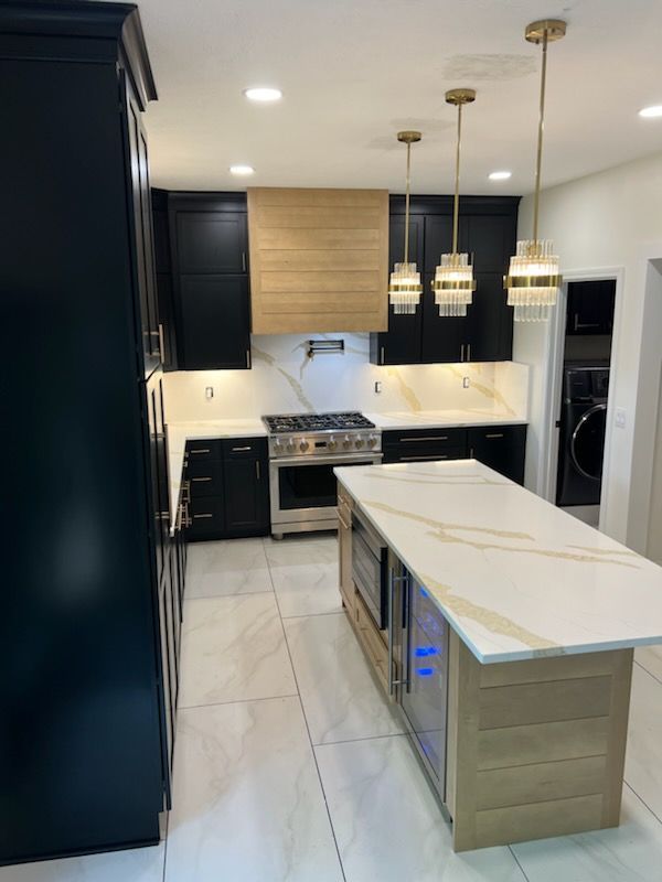 A kitchen with black cabinets and a large island in the middle.