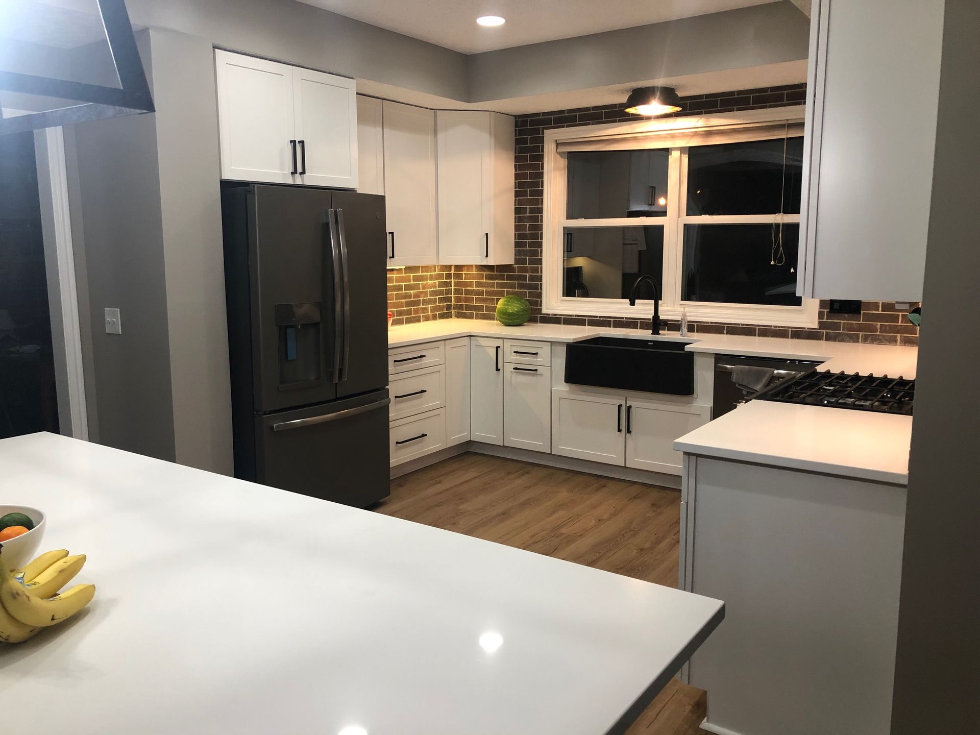A kitchen with white cabinets and a black refrigerator.