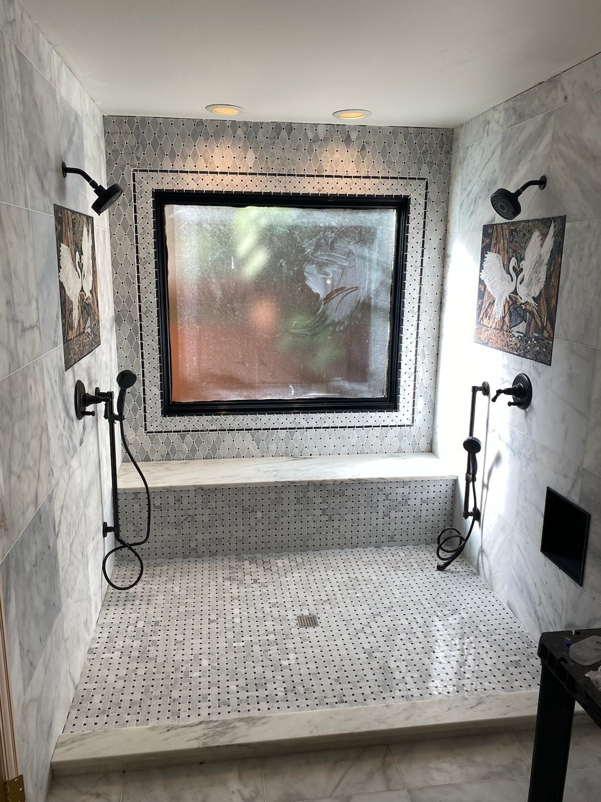 A bathroom with two showers and a large window.