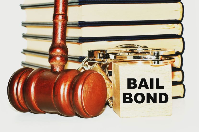Judge’s gavel beside handcuffs and a “BAIL BOND” sign with stacked law books
