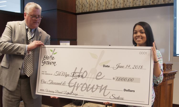 Mark Jeffrey, District Manager for Sodexo, presents a $1,000 check to TaMya Romero for her winning Home Grown Springfield design.