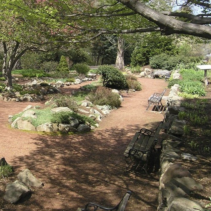 Garden space with blooming trees, flowers, and benches e at Elizabeth Park in West Hartford