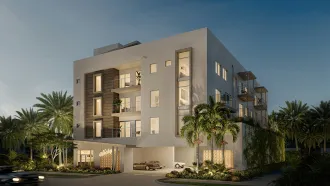 Modern white building with balconies and palm trees in a tropical setting.
