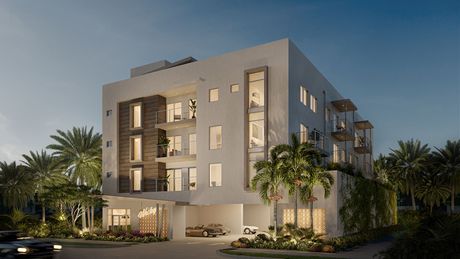 A modern, four-story white apartment building with a dark textured facade, balconies, and lush tropical landscaping.