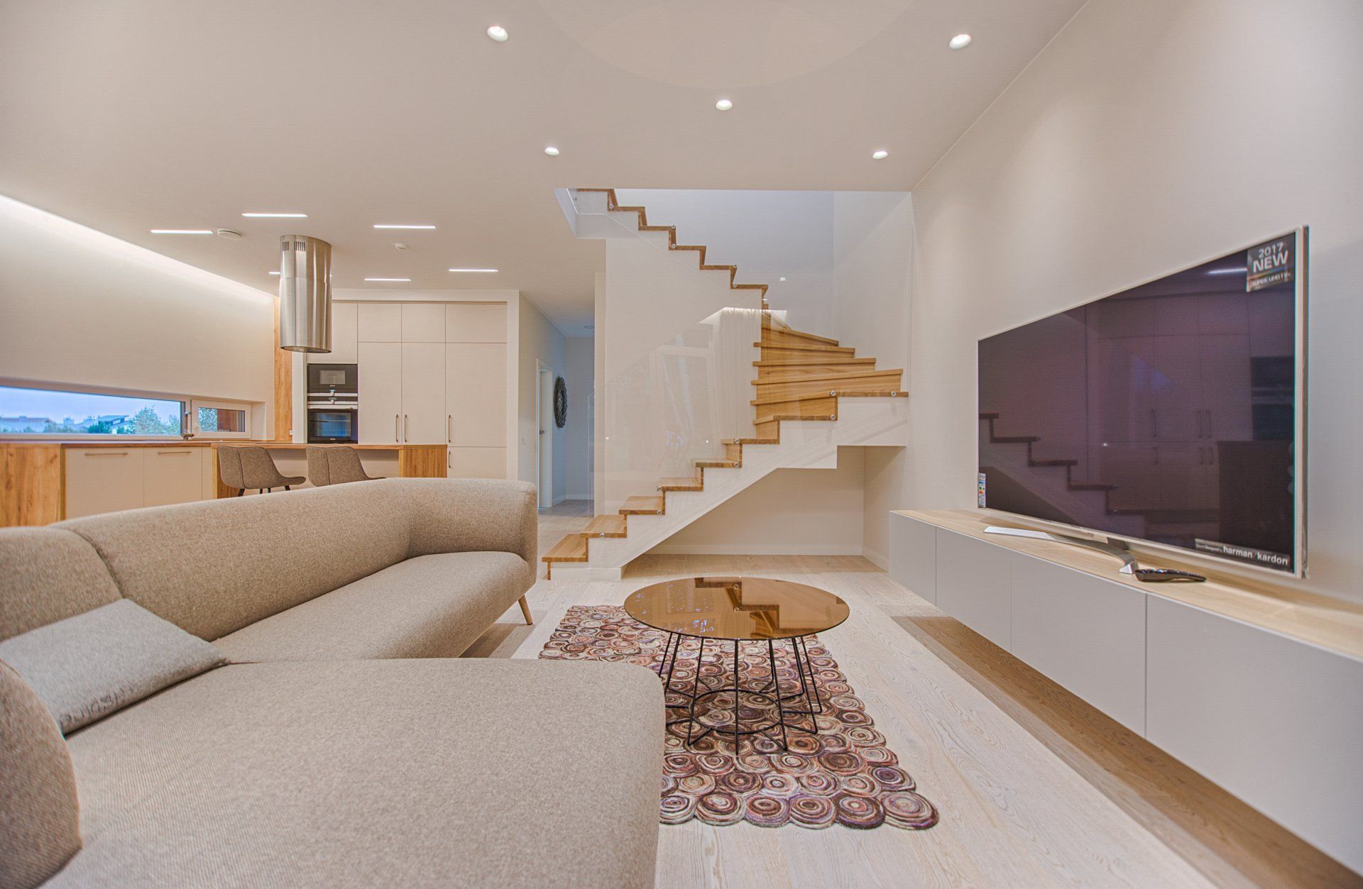 A living room with a couch , television , and stairs.