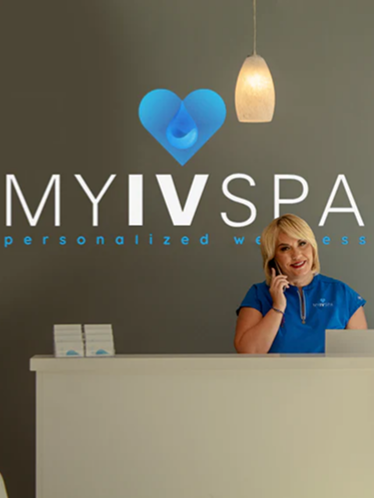 A woman at a spa reception desk, talking on the phone.