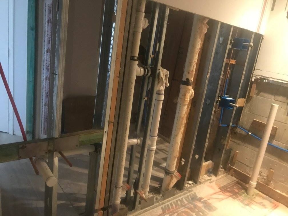 Interior view of open wall showing plumbing and framing during renovation.