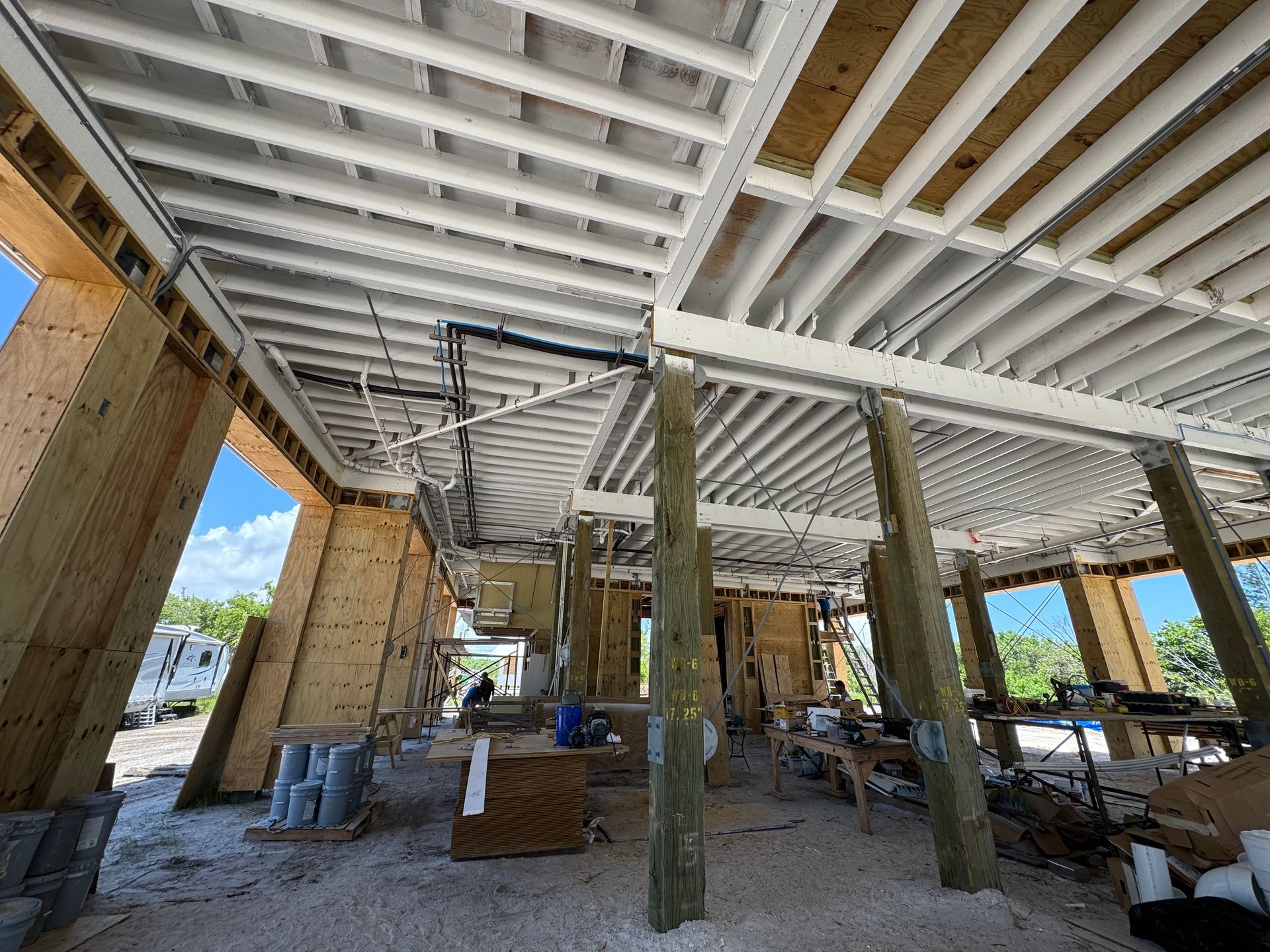 Interior of a construction site with exposed ceiling beams, support columns, and scattered building materials