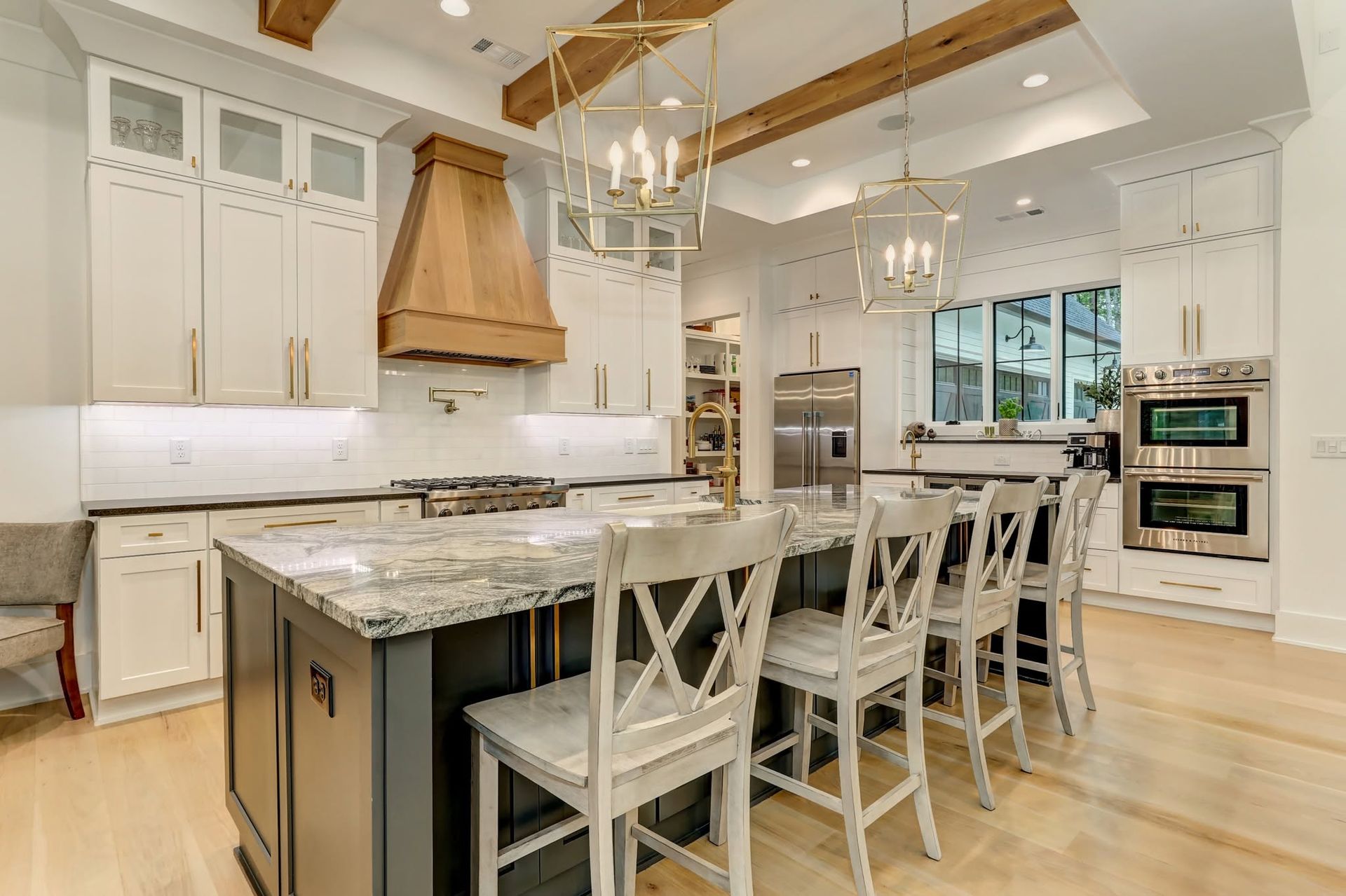 Bright modern kitchen with white cabinets, island, barstools, and stainless steel appliances