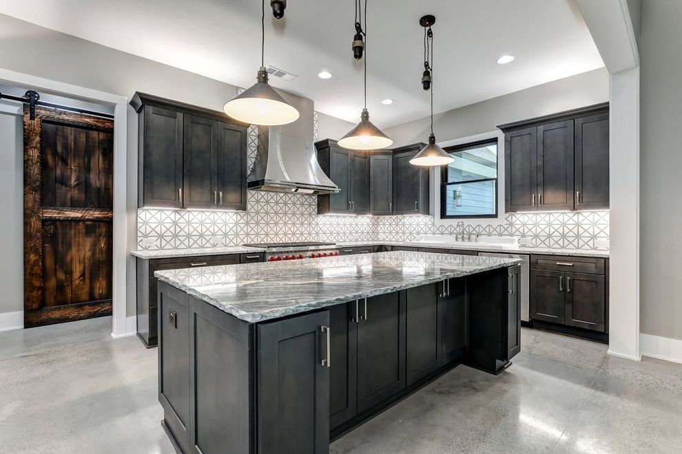 Modern kitchen with dark cabinets, large island, pendant lights, and gray tile backsplash
