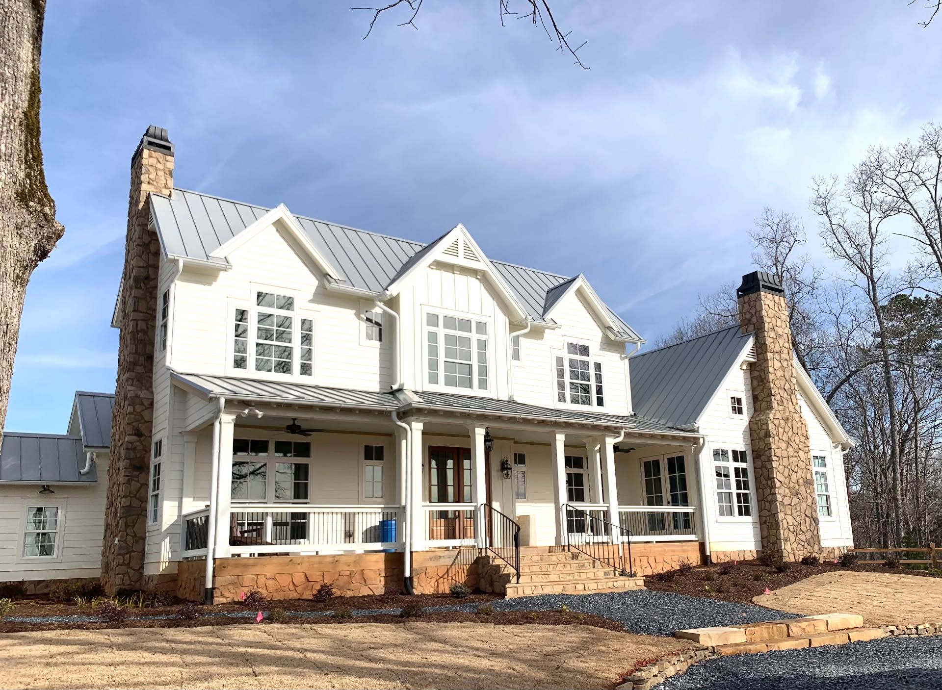 Large white two-story house with porches and dark roof on a sunny day