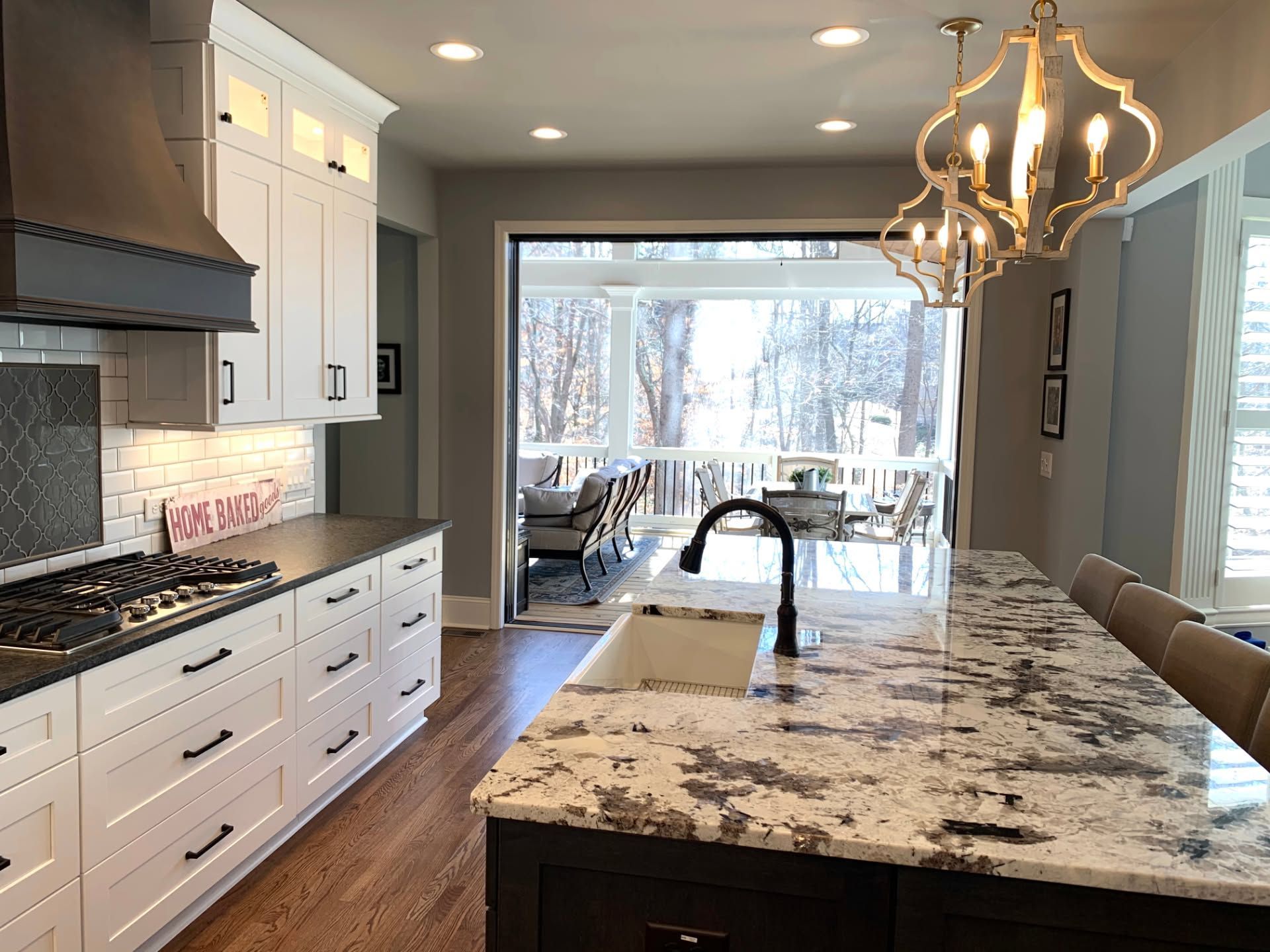 Modern kitchen with white cabinets, granite island, and large window overlooking a snowy view