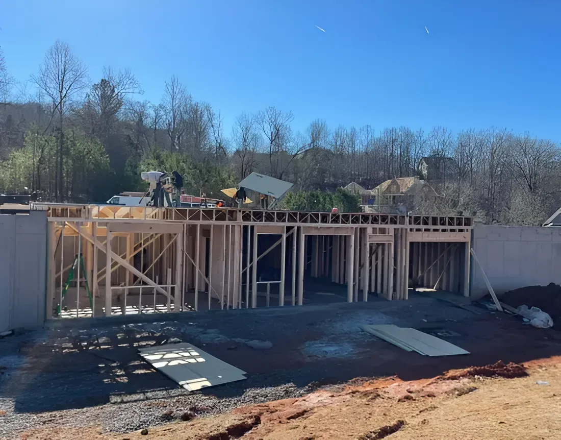 Construction site with wooden framing for a foundation, workers, and a clear blue sky above.