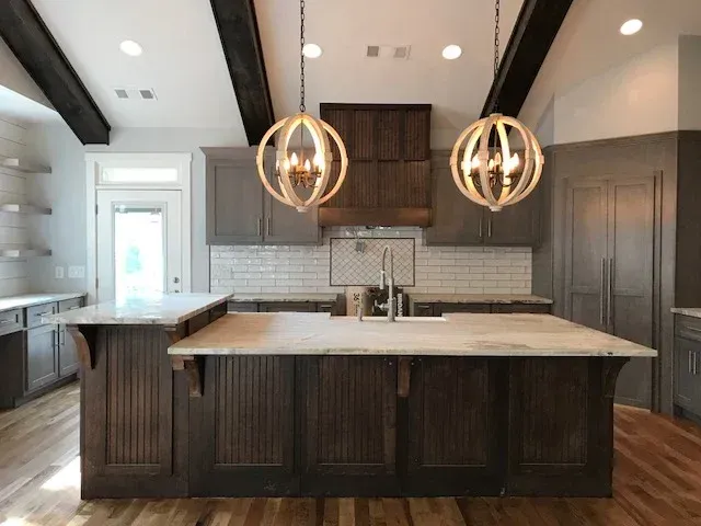 Modern kitchen with dark island, white countertops, and two pendant lights