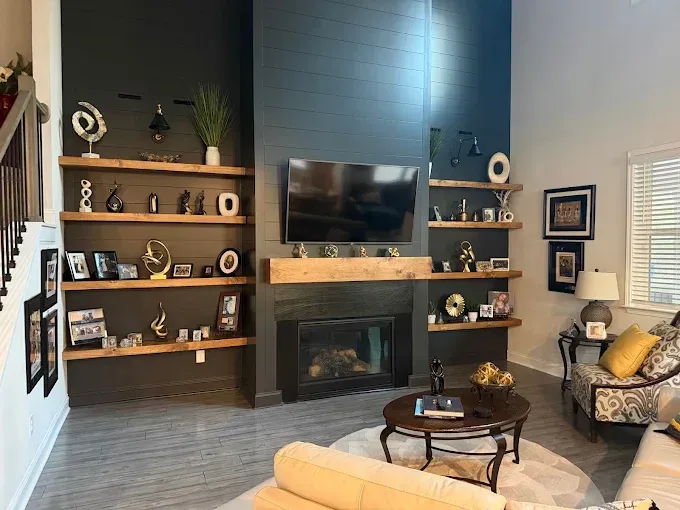 Modern living room with fireplace, wall-mounted TV, built-in shelves, and a round coffee table