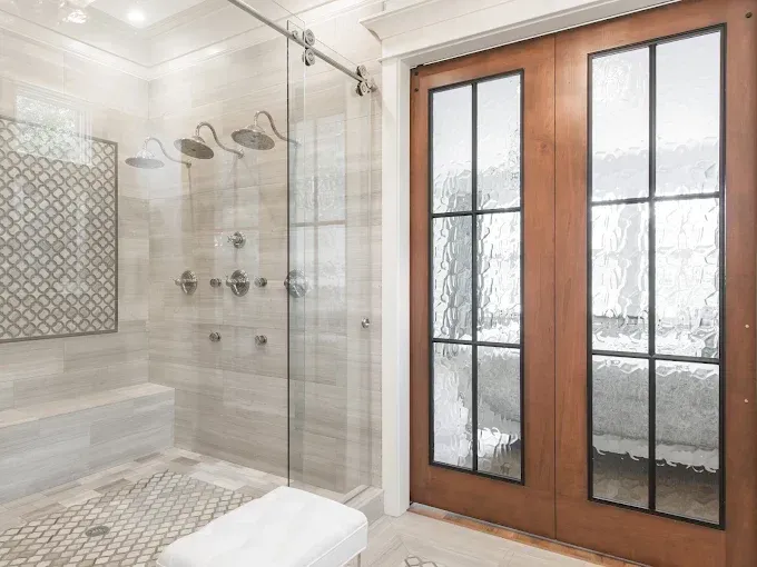 Modern bathroom with glass shower and wooden French doors opening to a snowy outdoor view