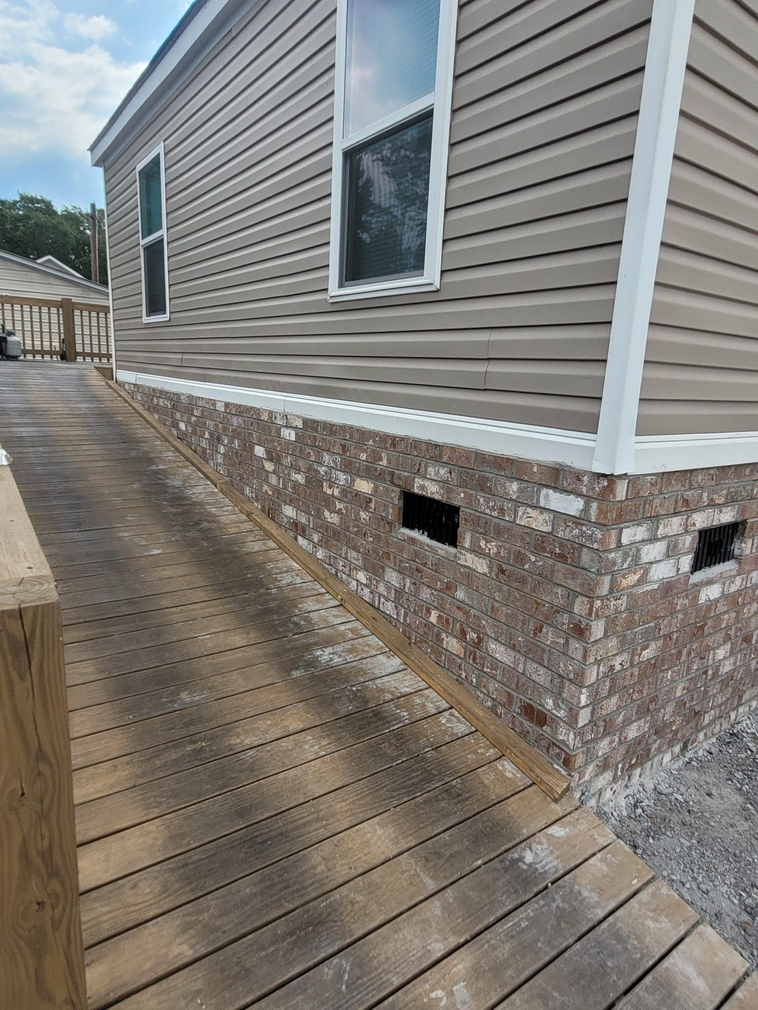A mobile home with a wooden deck in front of it.