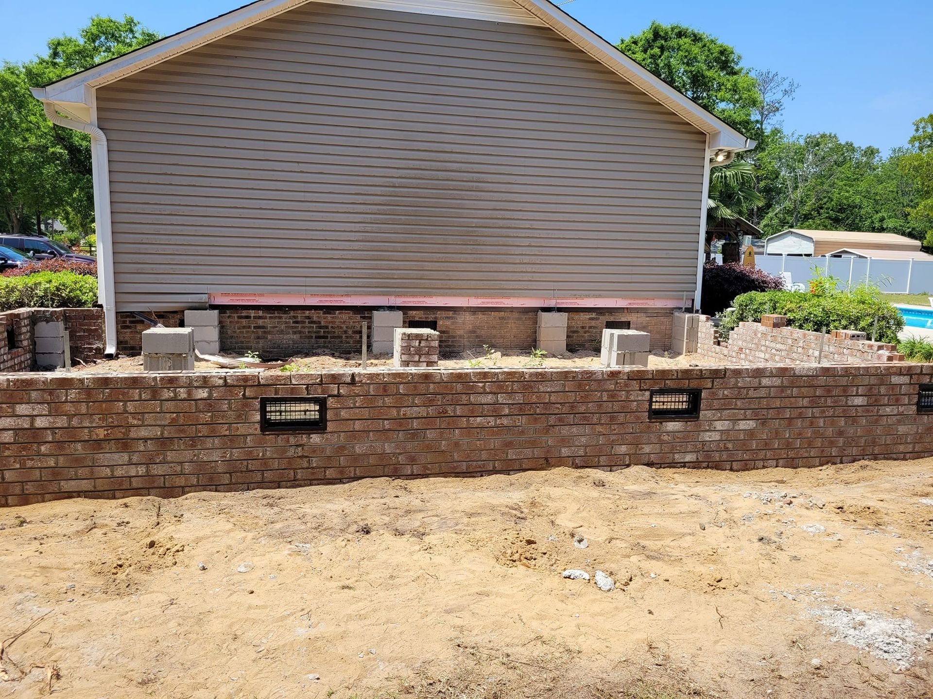 A brick wall is being built in front of a house.