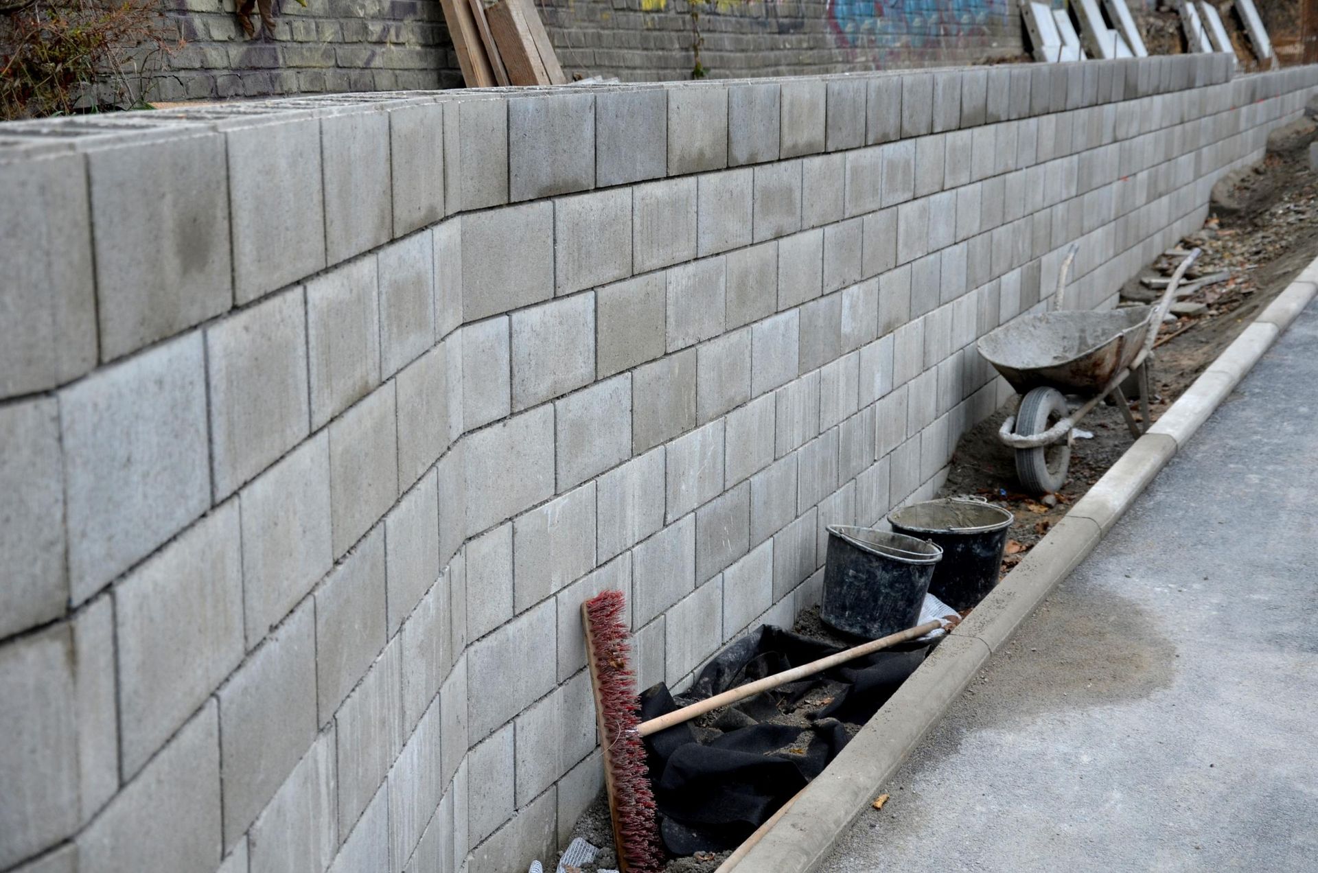 A brick wall is being built on the side of a road.