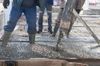 Workers pouring wet concrete onto a rebar grid at a construction site