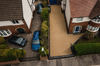 Aerial view of two suburban houses with driveways, parked cars, and front gardens.