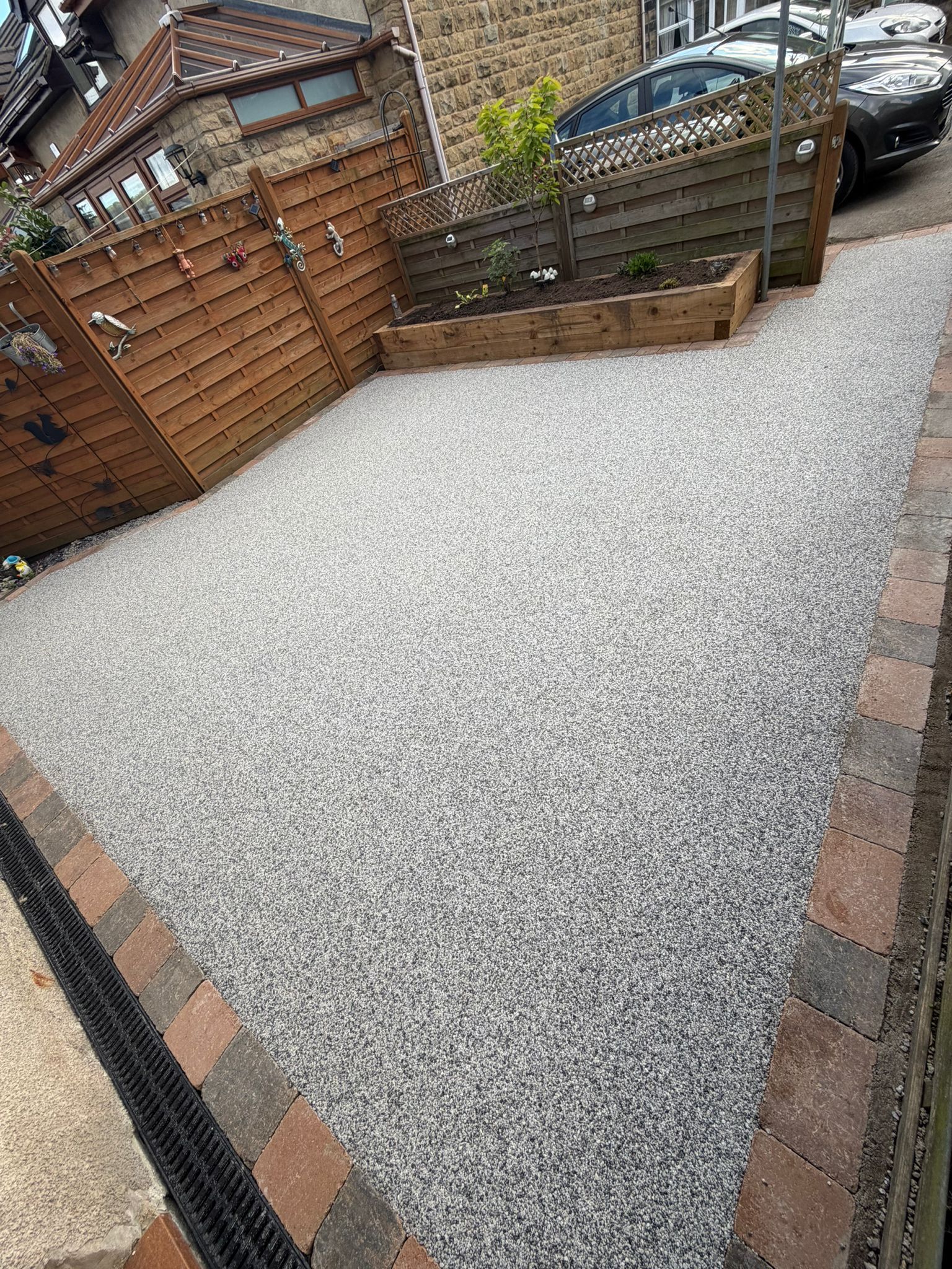 Gravel courtyard with brick edging, wooden fencing, and a raised planter