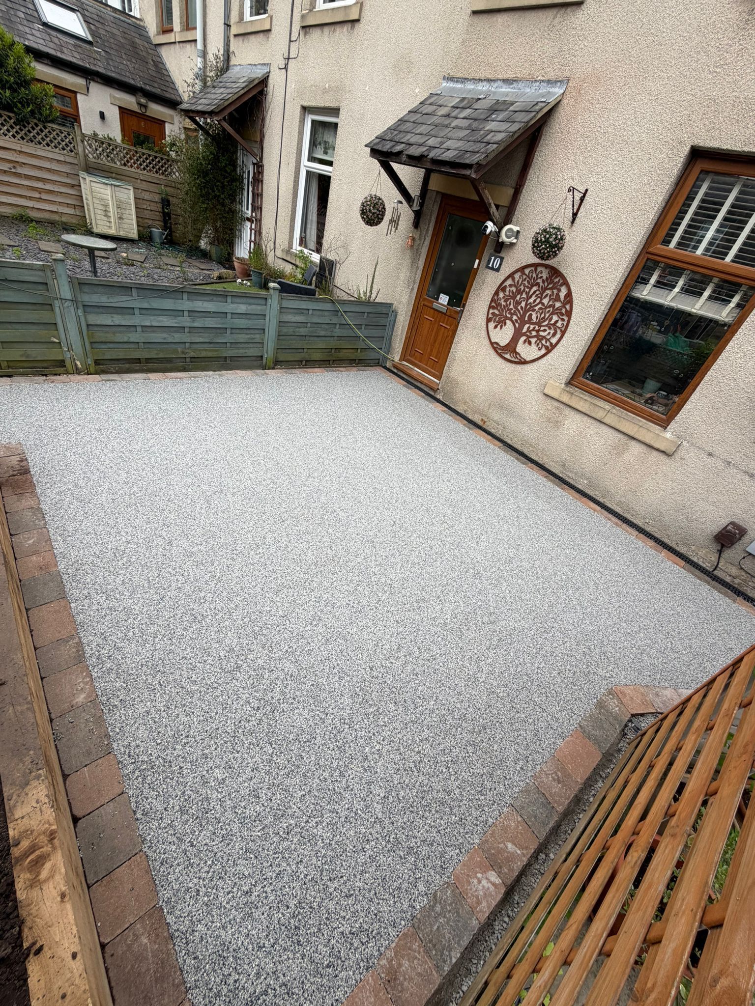 Small gravel courtyard with a house door, windows, and wooden planters along the edges