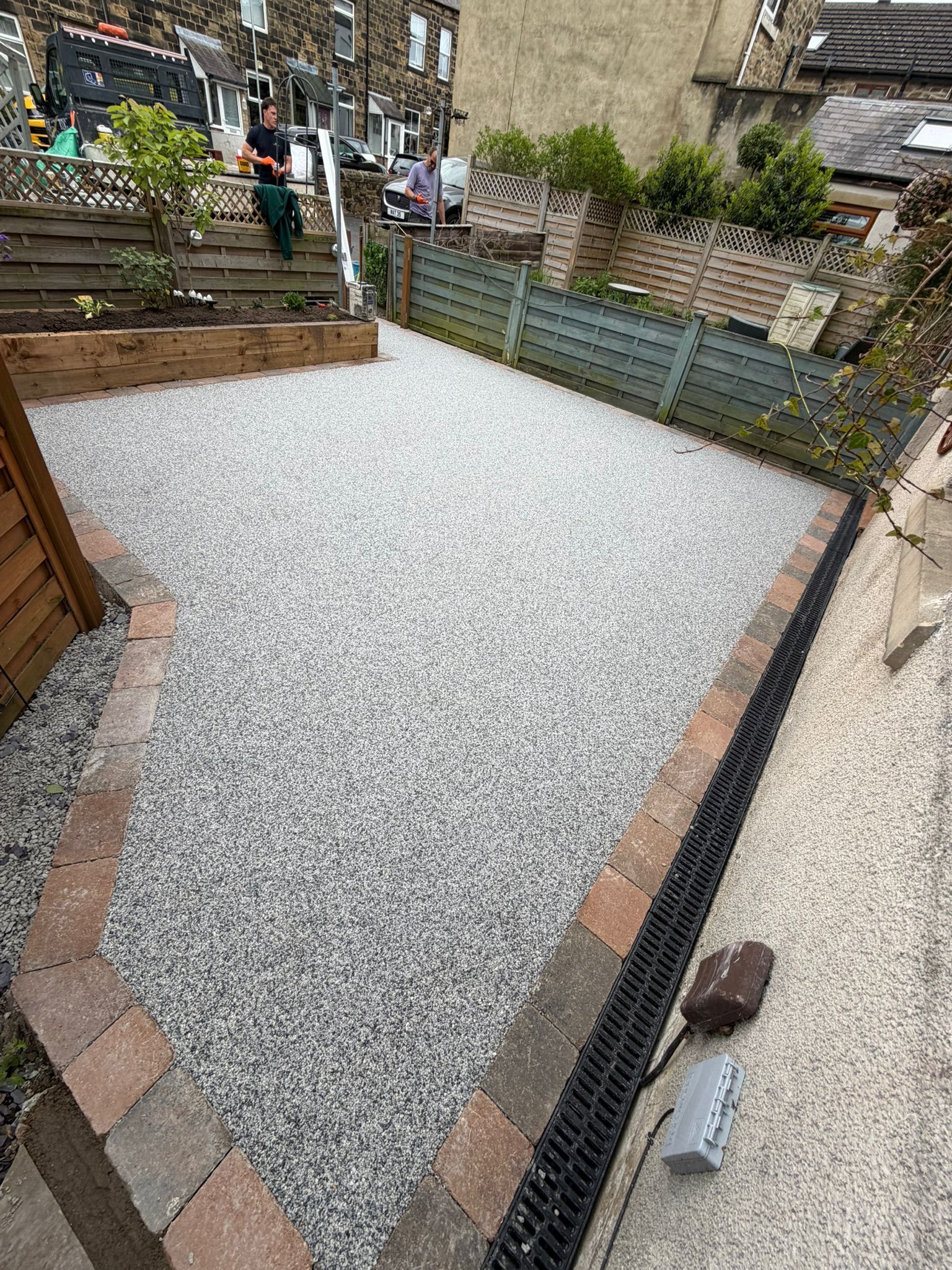Gravel front yard with brick edging, raised planters, and a sidewalk beside a house
