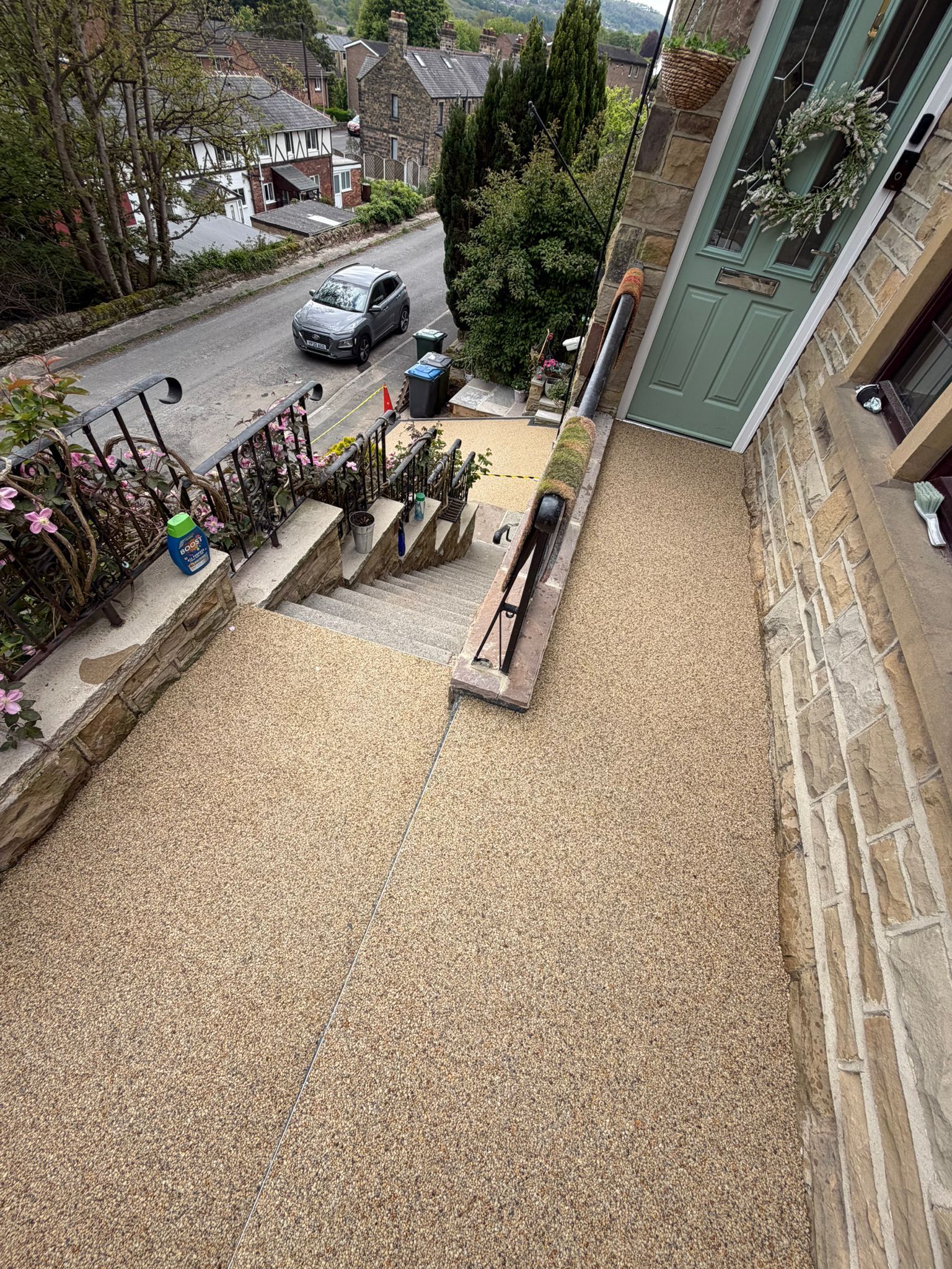 View from a window onto a street and stone steps beside a gravel courtyard with a glass door.
