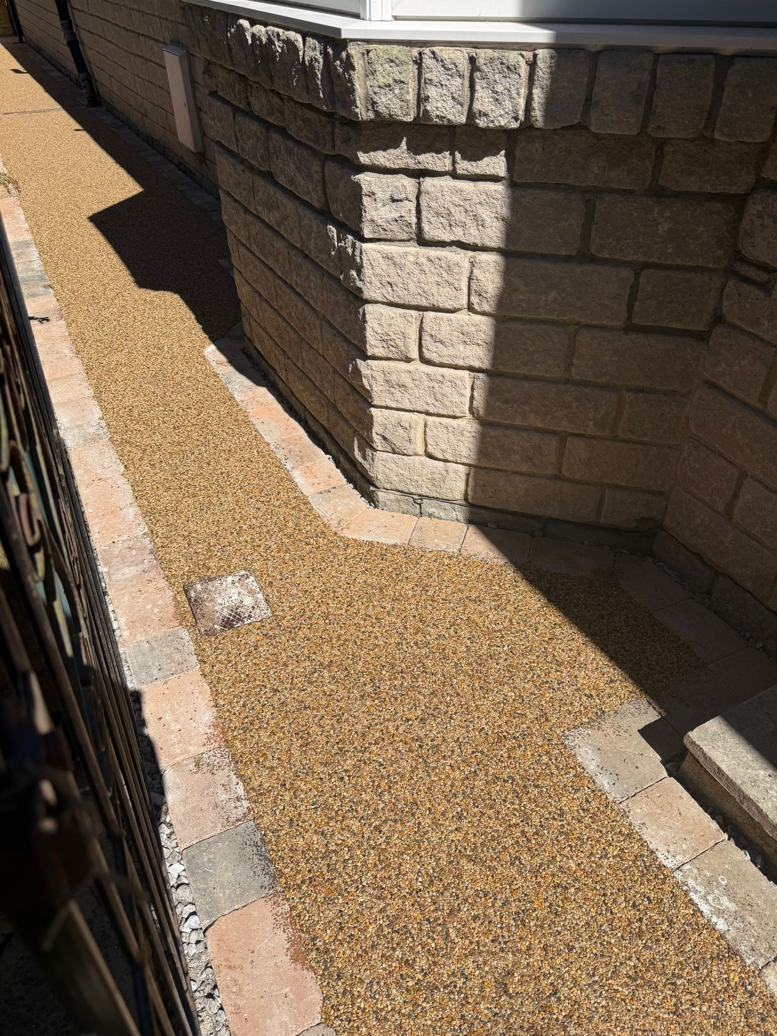Gravel pathway beside a stone retaining wall in bright sunlight