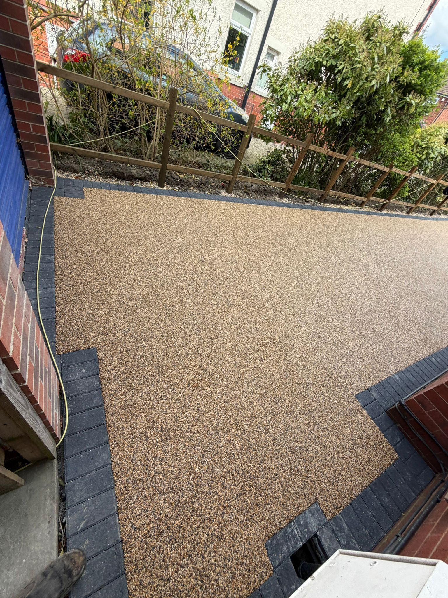Gravel-covered courtyard beside brick walls and green shrubs, viewed from above.