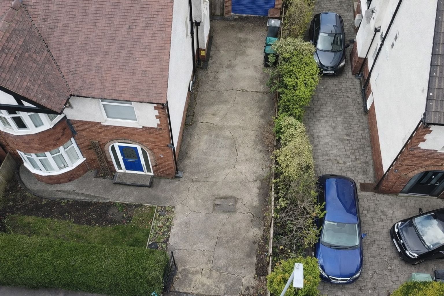 Aerial view of apartment buildings with a narrow driveway and several parked cars.