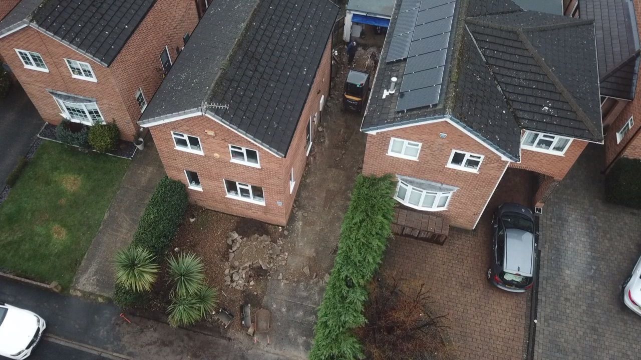Aerial view of brick houses with dark roofs and driveways in a residential neighborhood