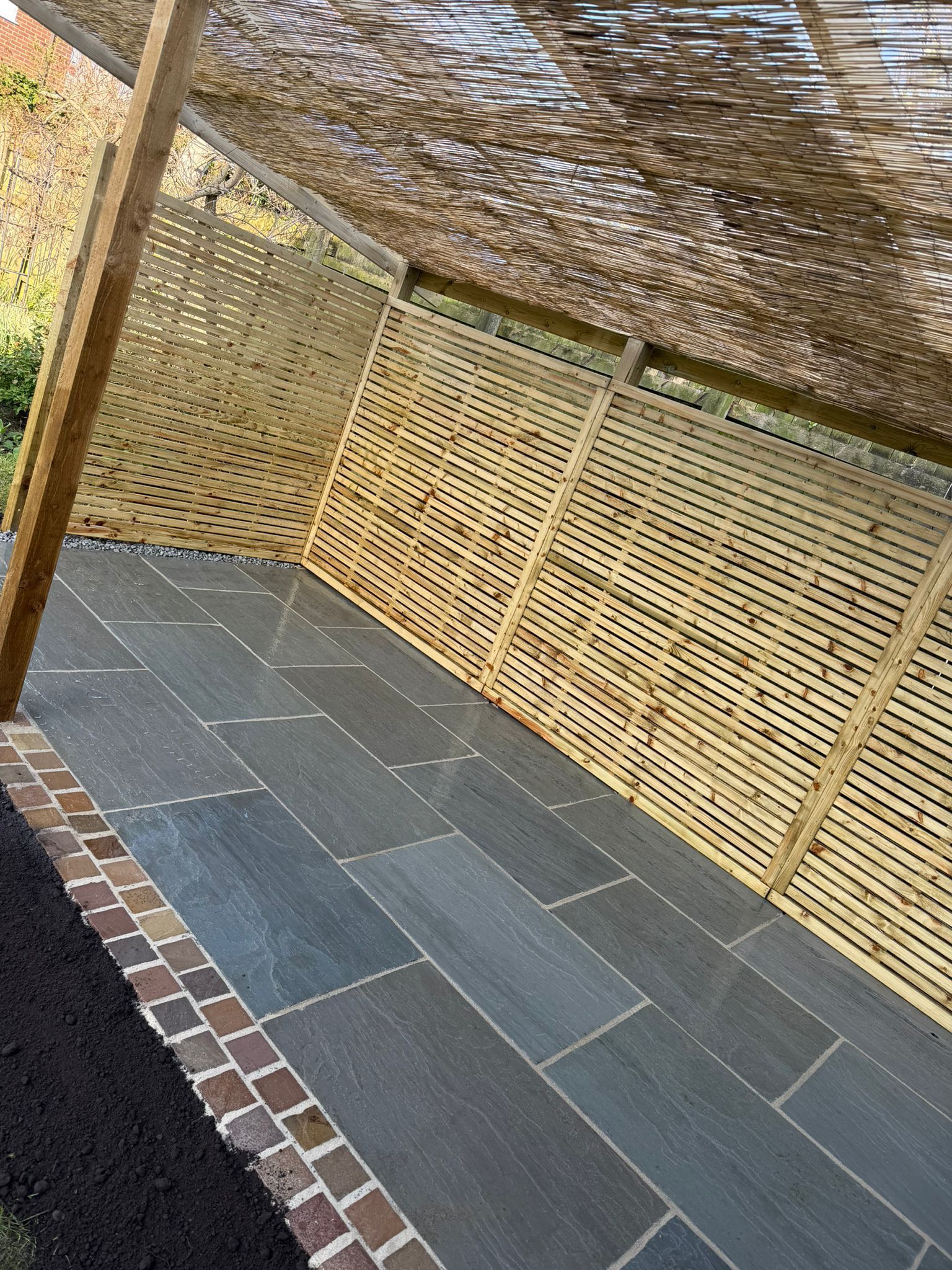 Outdoor patio with gray stone tiles, woven bamboo screens, and a camo-pattern shade canopy