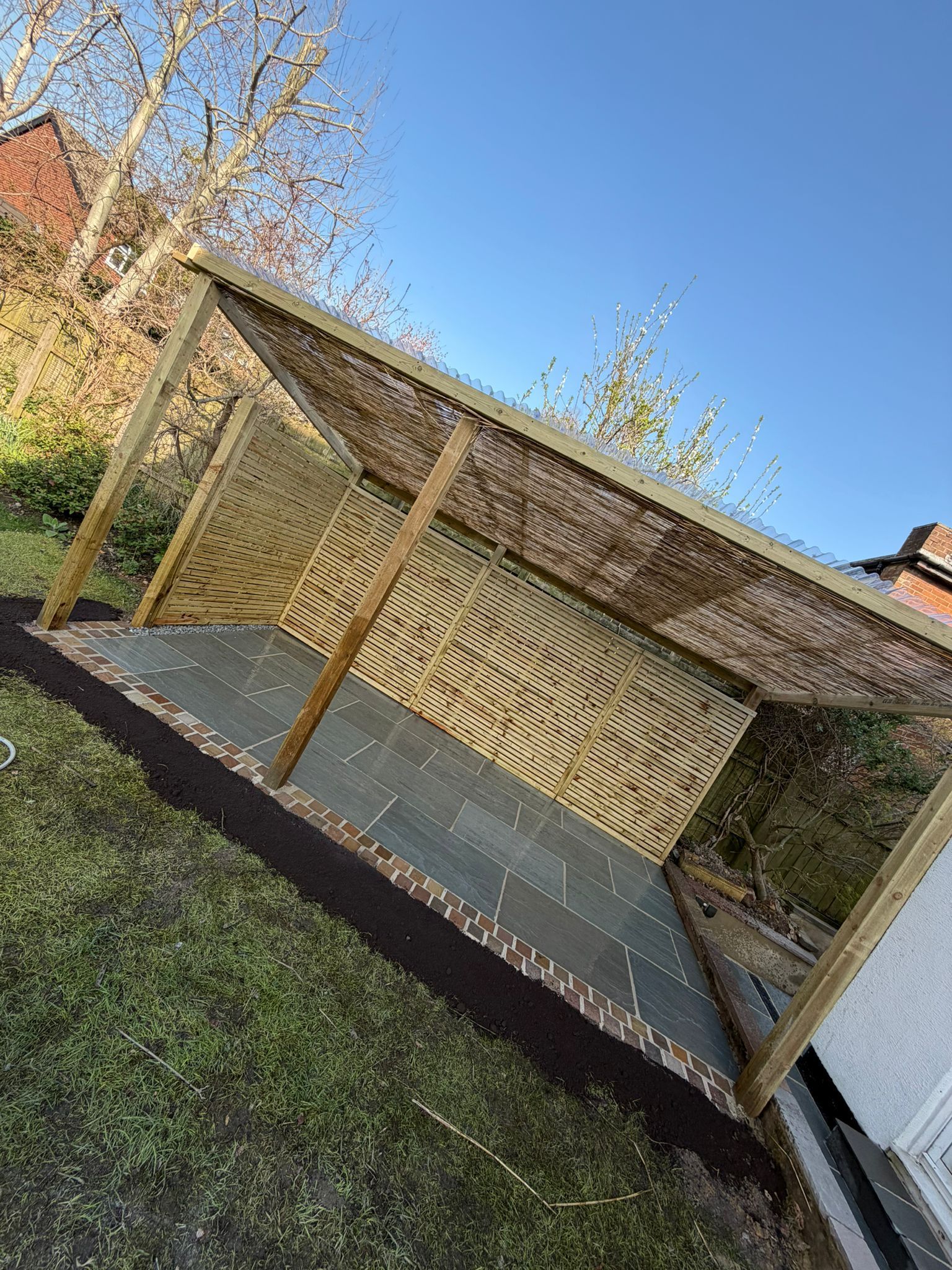 Tilted wooden carport with lattice wall and slanted roof in a grassy yard