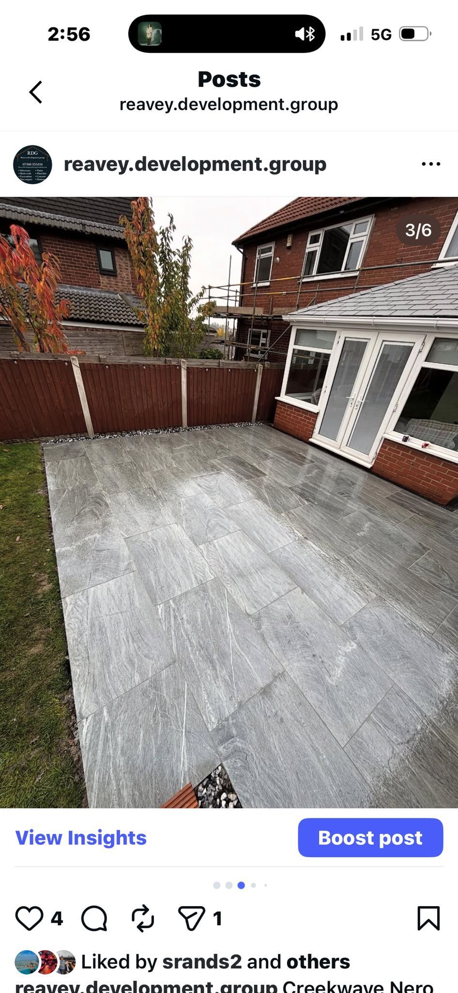 Freshly paved gray driveway beside a brick house with white-framed porch and fence