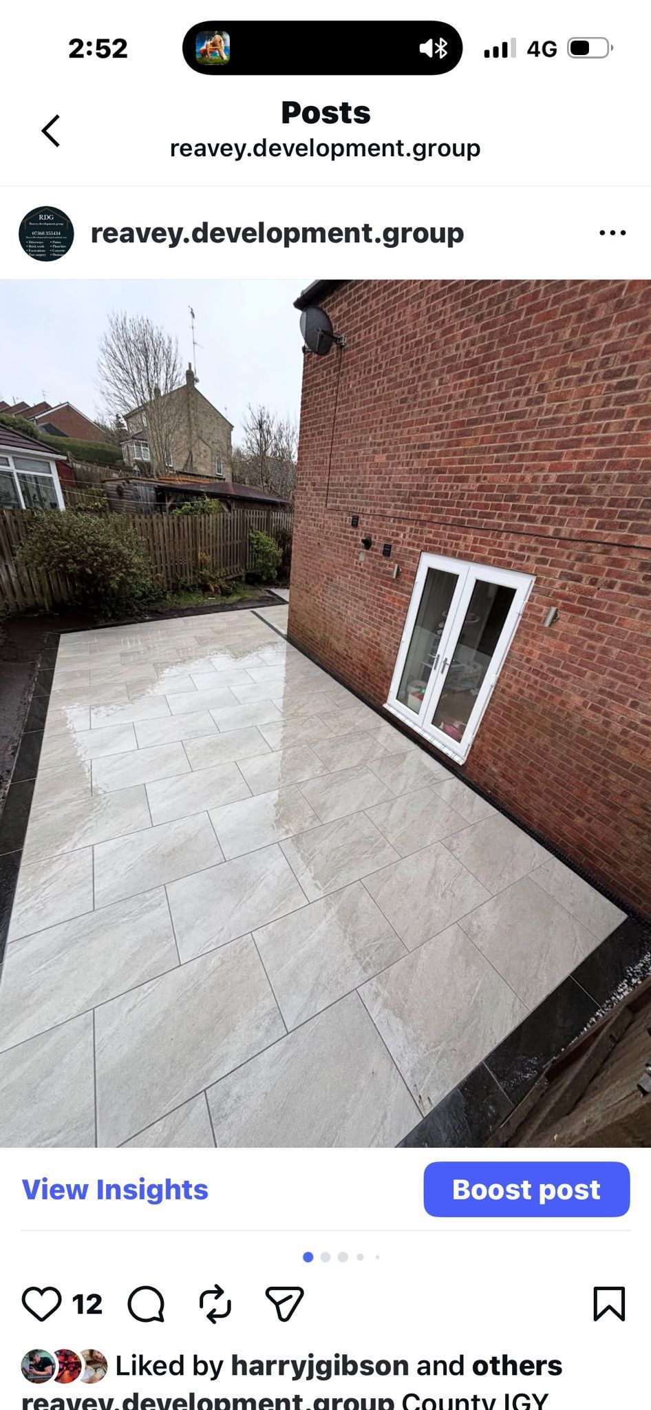 Rooftop terrace with white concrete floor beside a red brick wall and a leaning white-framed window panel.
